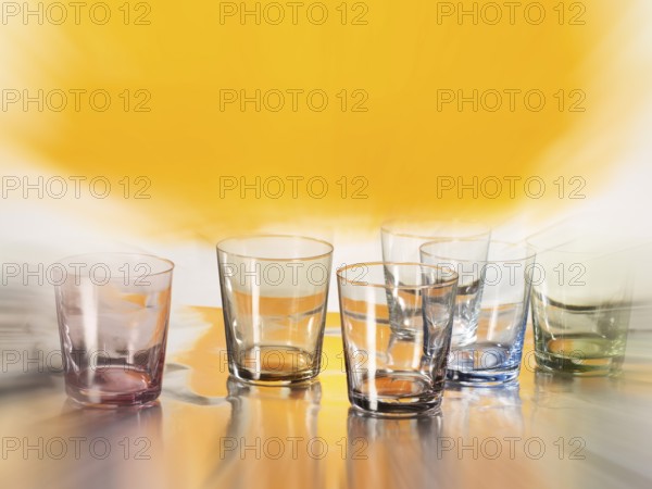 Various glasses on silver foil, yellow coloured area behind, zoom effect, studio shot