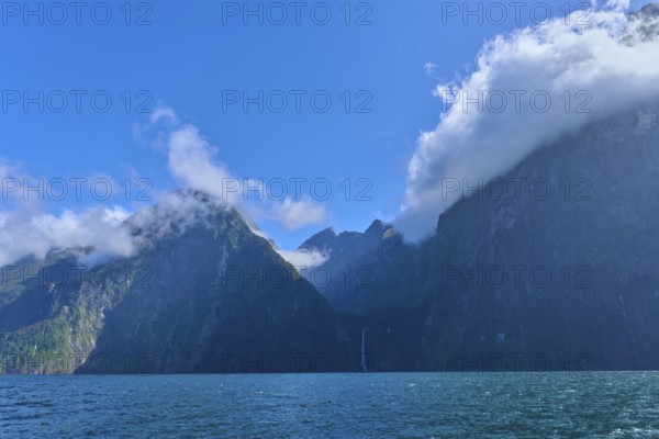 Twisted clouds envelop majestic mountains over the sea, fjord landscape, summer, Milford Sound, Te