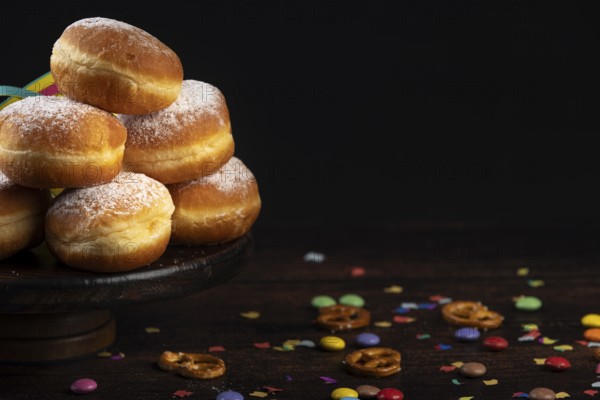 Doughnuts on a plate with scattered confetti and pretzels on a dark background
