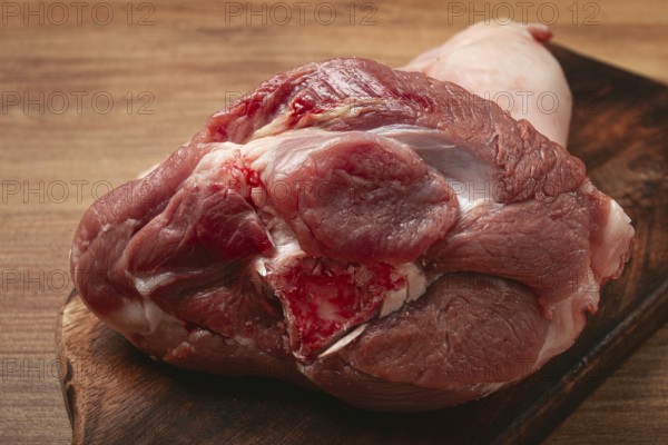 Raw pork knuckle, on a wooden chopping board, close-up, top view, no people