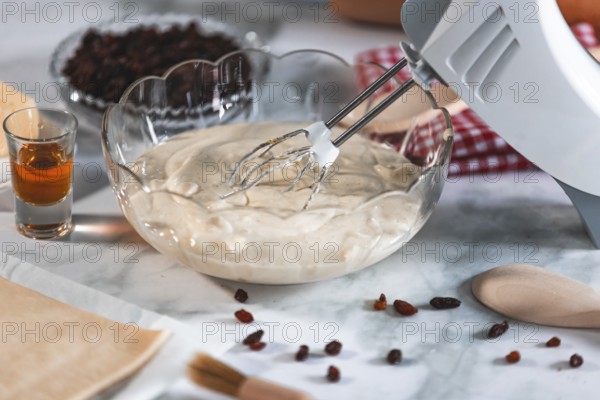 An electric mixer stirs cream of curd cheese, rum and sultanas next to it