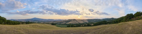 Typical Tuscan landscape in Val d'Orcia with hills, trees, fields, cypresses and farm road in