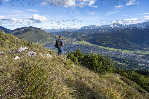 View of Garmisch-Partenkirchen and mountain panorama, mountaineer on hiking trail to Kramerspitz,