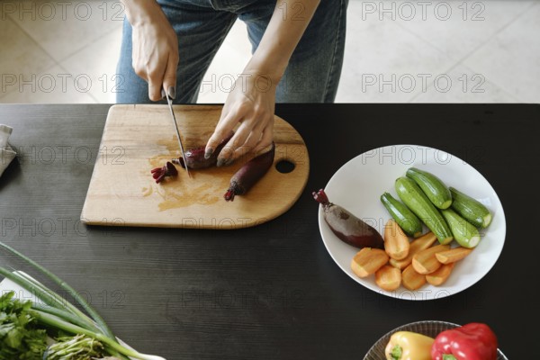 Close-up of female hands chopping fresh baby beetroot on wooden board