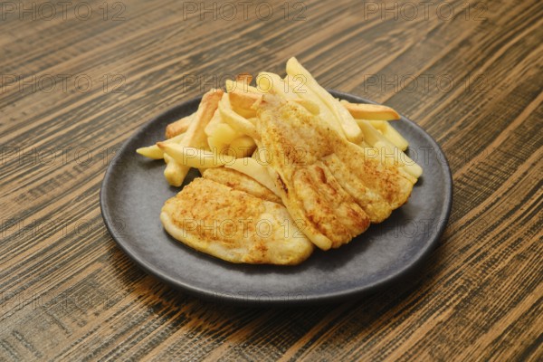 A plate holds two golden-brown pieces of fried fish alongside a generous serving of crispy french