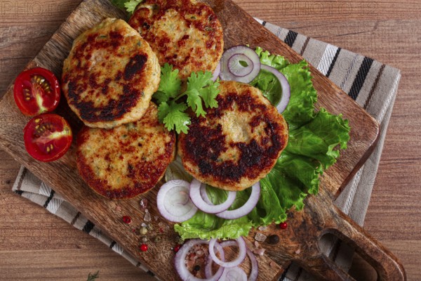 Fried chicken cutlets, minced chicken, with vegetables, on a cutting board, with vegetable salad,