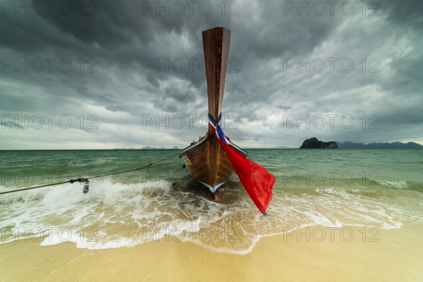 Longtail boat on the beach, dark rain clouds behind, Koh Ngai Island, Andaman Sea, Satun Province,