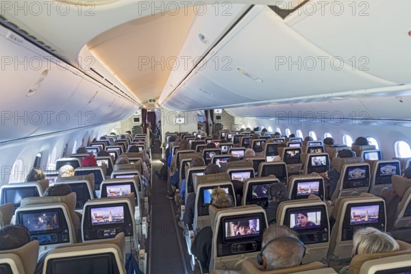 Etihad airline aircraft, interior, rows of seats with passengers. Boeing 787 aircraft on a flight
