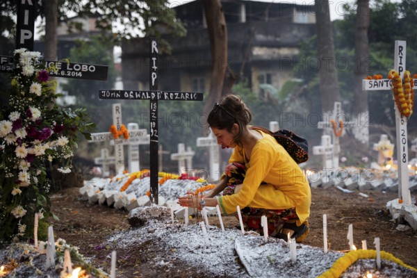 People from Christian community light candles and offer prayers on the grave of their relative