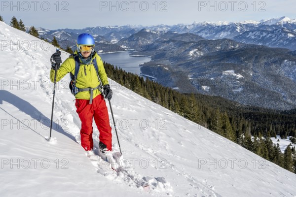 Skiers skiing down the Simetsberg, view of Walchensee and mountain panorama, Estergebirge, Bavarian