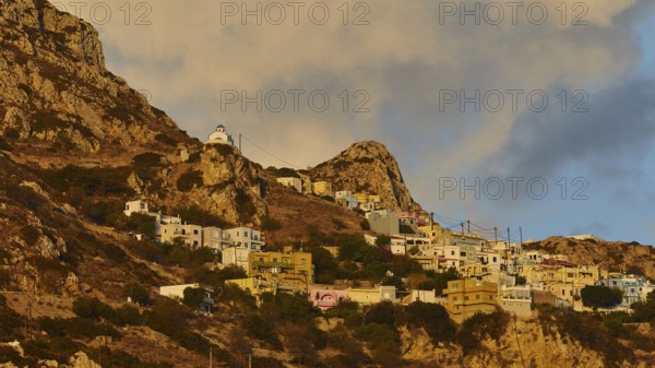 Houses of a village placed in steps on a rocky hill under a morning sky, mountain village Menetes,