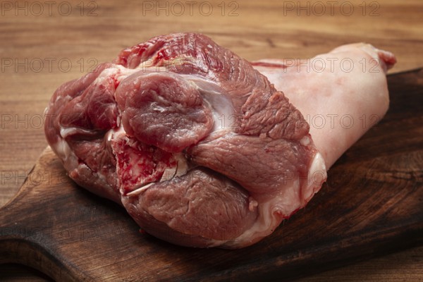 Raw pork knuckle, on a wooden chopping board, close-up, top view, no people