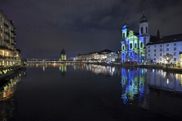 Water tower and Jesuit church on the right with light installation, on the Reuss at dusk, Old Town,