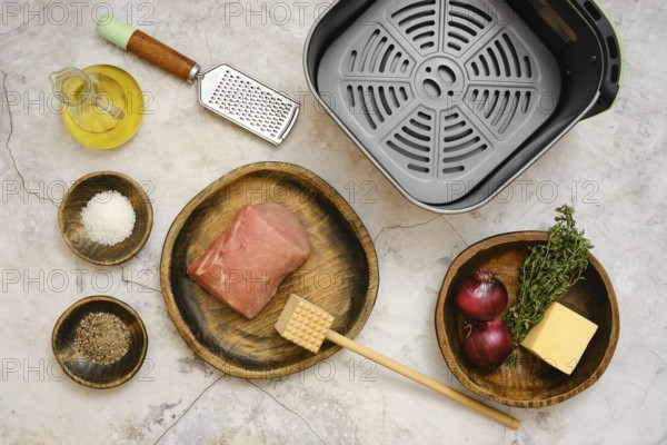 A raw pork loin on a wooden plate beside bowls filled with salt, pepper, and fresh thyme. An onion,