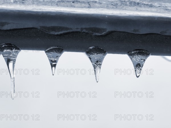 Four icicles hanging from a railing, macro, unusually cold winter 2010, symbolic photo winter