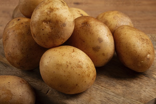 Raw potatoes, scattered on a chopping board, close-up, no people