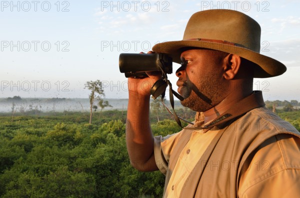 Local man looking through binoculars, Kasanka National Park, Zambia, Africa