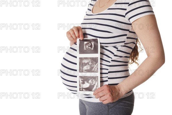 Pregnant woman standing and holding her ultrasound baby scan picture isolated on white