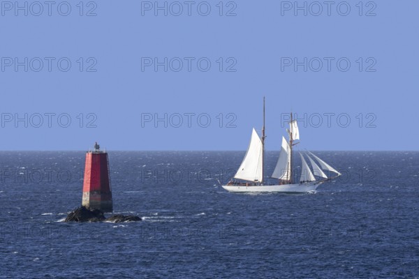 Sailing ship passing red sea mark, seamark, navigation mark on the shallows Les Vieux Moines at