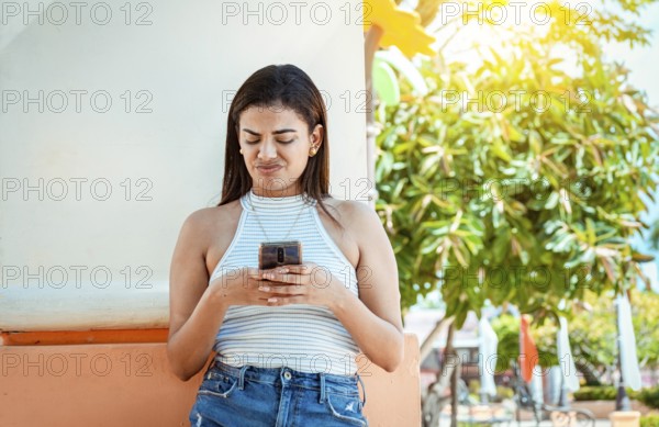 Girl with the cell phone receiving an unpleasant message. Young woman with cell phone reading a