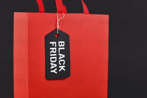 Black Friday sale label on red paper shopping bag on black background