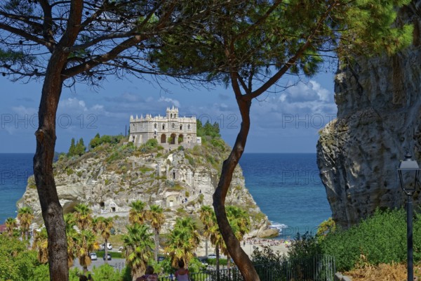 View through pine trees to the medieval church Santuario di Santa Maria dell Isola di Tropea built