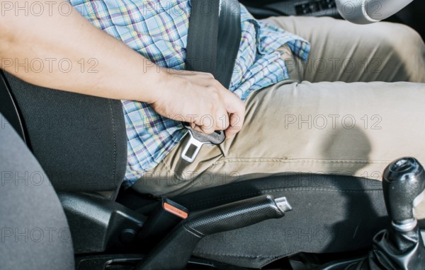 Close up of person hands putting on the seat belt. Close up of driver hands fastening the seat