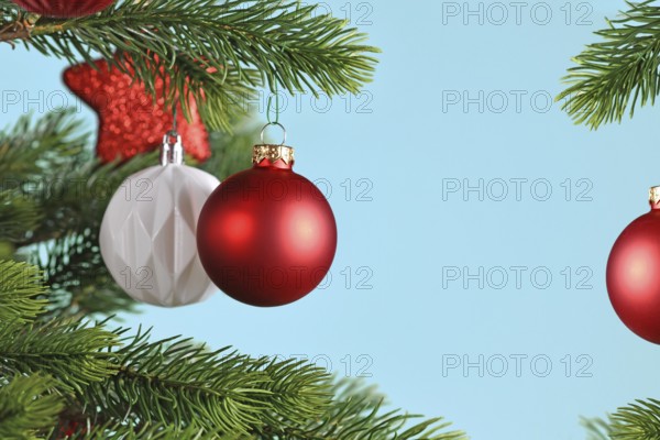 Red Christmas baubles on Christmas tree on blue background with copy space