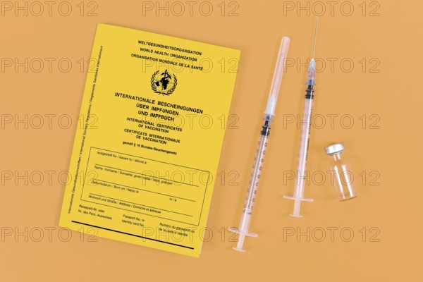 Vaccine concept with syringes, vial and yellow international certificate of vaccination on orange