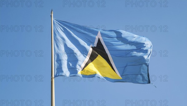 The flag of St Lucia, Caribbean, flutters in the wind, isolated against a blue sky