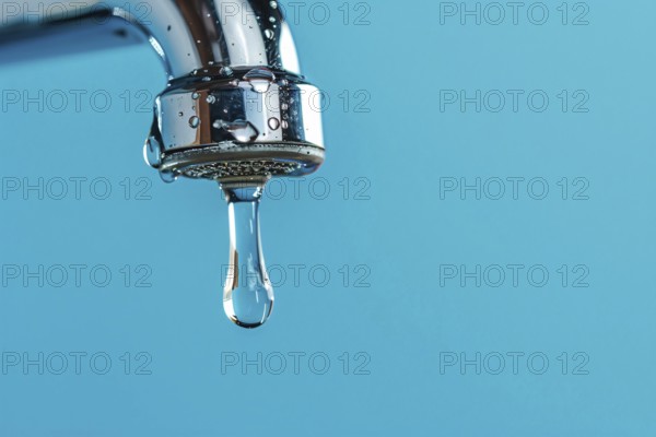 Single drop of water coming out of water tap on blue background. KI generiert, generiert, AI