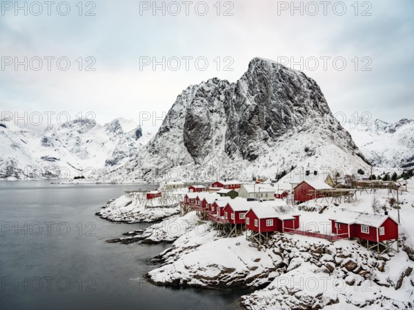Rorbuer huts of Hamnoy at the fjord, snowy mountains in the background, Hamnøy, Reine, Moskenesøya,