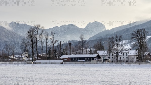 Snow-covered village in front of a mountain range with a peaceful winter atmosphere, Bad Feilnbach,