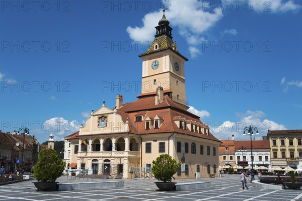 A busy town square with a town hall and a large clock on a clear day, Old Town Hall at Piata
