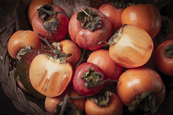 Fresh persimmon in a basket, with leaves, top view, no people
