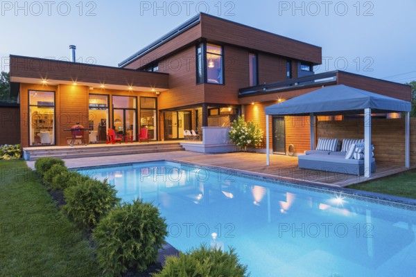 Rear of modern cube style home with stained horizontal wood cladding, in-ground swimming pool and