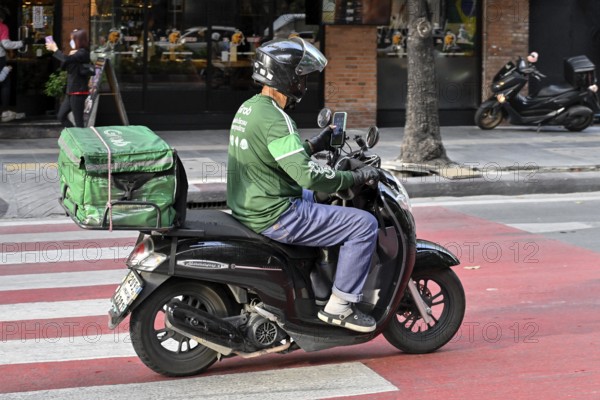 Grab scooter driver typing on mobile phone