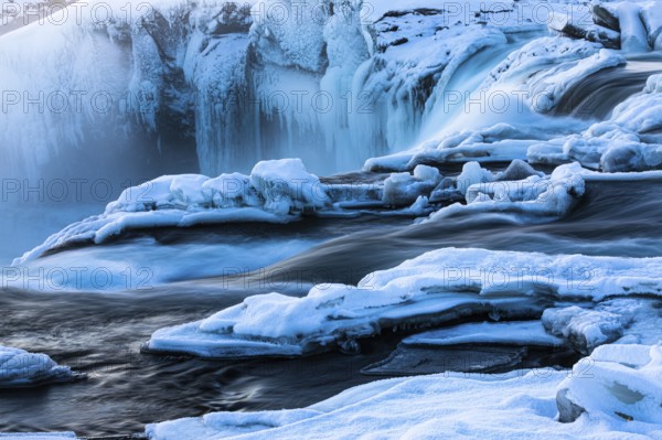 Icefall at the edge of the Godafoss waterfall at dawn, snow-covered landscape, Northern Iceland