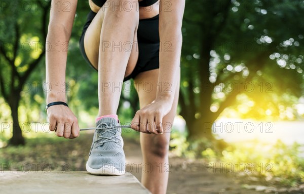 Close-up of sporty woman tying her shoes. Athletic girl tying her shoe laces in a park. Runner girl
