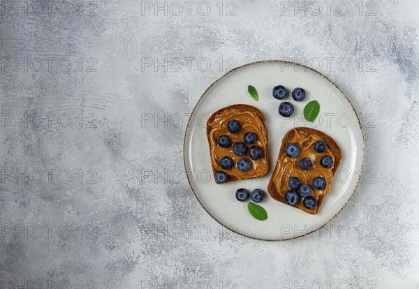 Rye bread with peanut paste and fresh blueberries, top view, no people