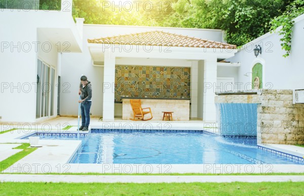Man cleaning swimming pool with suction hose. Pool maintenance and cleaning with vacuum hose.