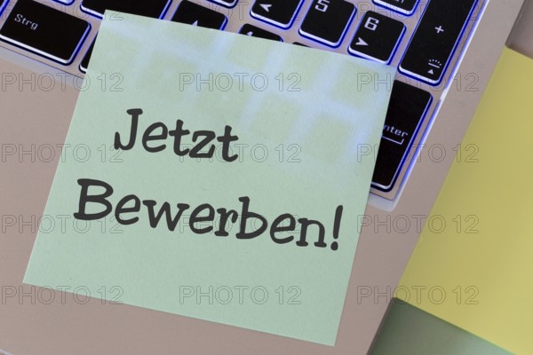 Notepad with the words APPLY NOW on a laptop