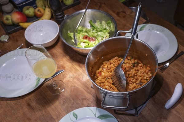 Salad and freshly cooked pasta with tomato sauce in a pot on the table, Baden-Württemberg, Germany,