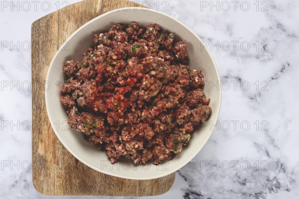 Raw minced meat, marinated with spices and herbs, in a bowl, minced meat with spices, top view,