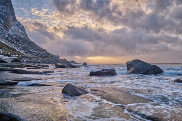 Rocks on beach of fjord of Norwegian sea in winteron sunset. Utakliev beach, Lofoten islands,
