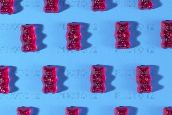 Red gummy bears in rows, on a blue background