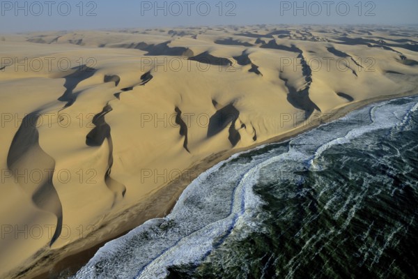 Aerial view, dunes in Namib desert, Atlantic Ocean, waves breaking on Namibian coast south of
