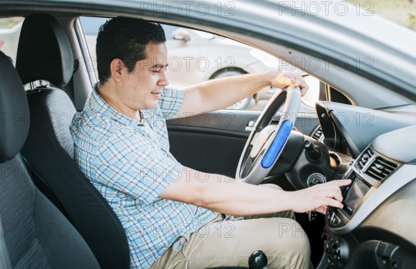 Driver man changing the radio station. Smiling driver tuning into the radio station. Distracted