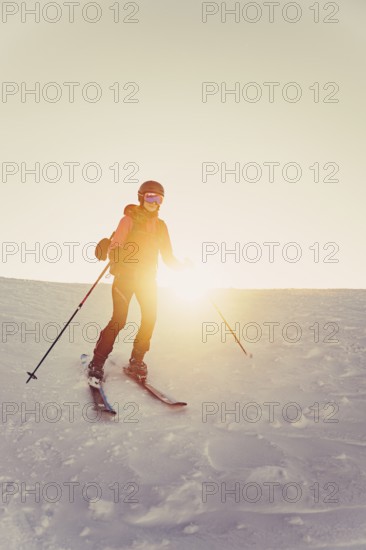 A woman's ski tour at sunrise on the Tegelberg in the Allgäu in the Ammergebirge, Bavaria, Germany,