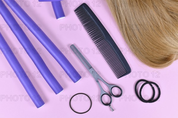 Hair styling concept with dark blond hair, elastic hair ties, comb, thinning shears, and papillote